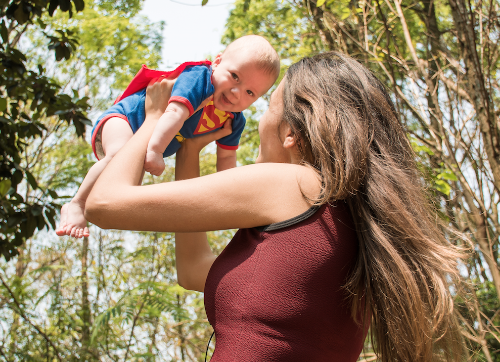 Image of woman holding baby in Superman costume