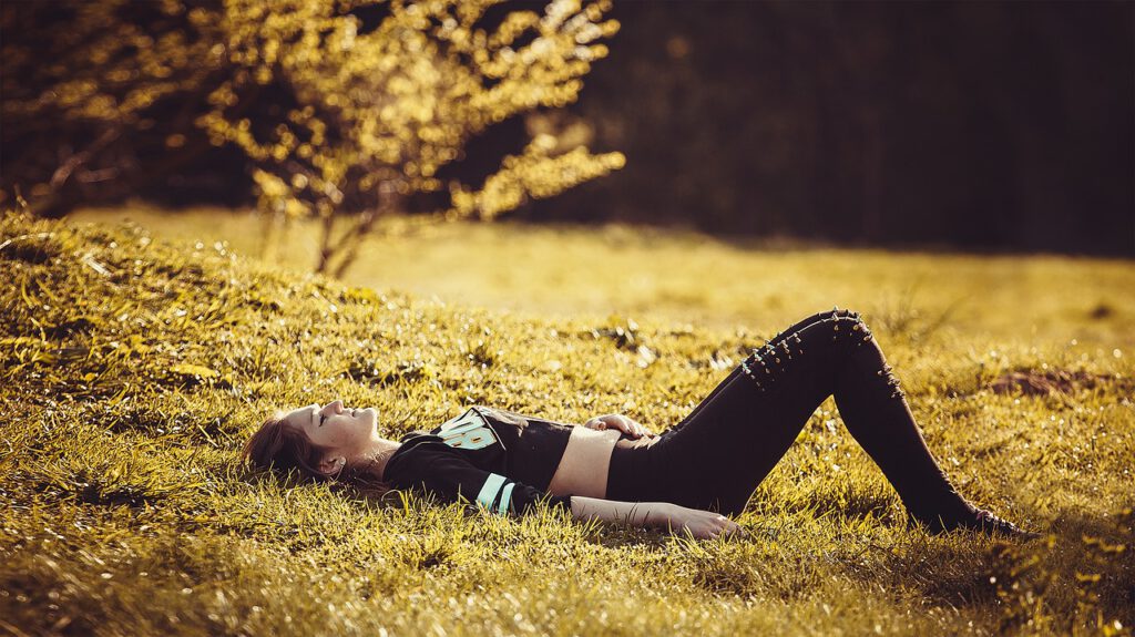 Image of woman laying in a field of grass under a tree