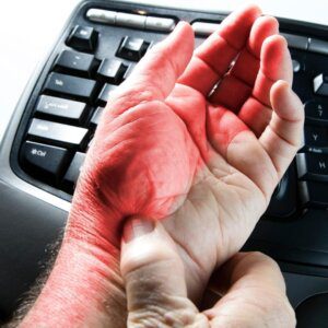 photo of person with carpal tunnel with their hand on a keyboard. 