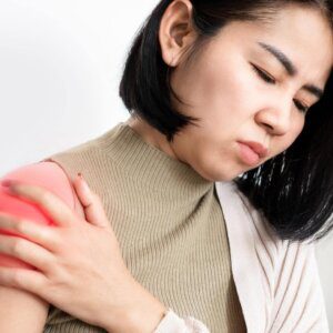 Photo of woman in  holding her shoulder due to painful frozen shoulder. 